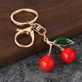 Llavero de cereza minimalista con hoja verde sobre fondo de madera y piedra - Rojo Pequeño (Brillante)