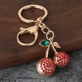 Detailopname van kersen sleutelhanger met rode kristallen en gouden metalen sluiting - Rood