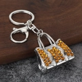 Sparkling silver handbag keychain with orange rhinestones and lobster clasp on stone background - Silver Yellow Stone