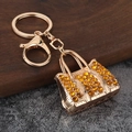 Exquisite golden handbag keychain with amber rhinestones on a dark wooden stand - Gold Yellow Zirconia