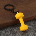 Detailed view of yellow 45 LB dumbbell keychain with matte texture and black metal ring - Yellow