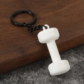 Macro shot of white dumbbell keychain with 45 LB engraving on wooden surface - White