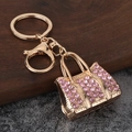 Detailed macro view of a golden handbag keychain featuring shimmering pink rhinestones - Gold Pink Zirconia