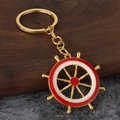 Gouden nautische scheepswiel sleutelhanger met rood-wit emaille op houten achtergrond - Goud Rood