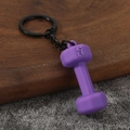 Detail of purple matte 45LB dumbbell keychain with black metal ring on wooden surface - Purple