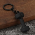 Detail of matte black dumbbell keychain featuring 45 LB weight engraving and metal chain - Black