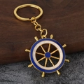 Detailopname van een gouden roerwiel sleutelhanger met blauw en wit email op hout - Goud Blauw