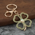 Detail of gold four-leaf clover keychain with green crystals and sparkling rhinestone - Green Zirconia