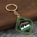 Dettaglio di un portachiavi dorato con ciondolo in smalto Kaaba e accenti verdi e neri - Verde