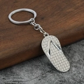 Detailed close-up of a silver flip-flop keychain with non-slip texture on a wooden block - Silver