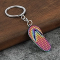 Rainbow plated flip flop keychain made of alloy metal on a rustic wooden surface - Rainbow