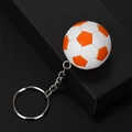 Dettaglio di un portachiavi calcio 3D con trama arancione e bianca su scatola nera - Arancione & Bianco