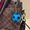 Dettaglio del portachiavi a pallone blu e nero appeso a una borsa a mano intrecciata - 3.8CM / Blu