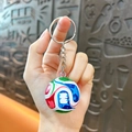 Handheld view of a soccer keychain featuring multi-colored patterns for World Cup fans - Colorful