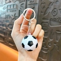Classic black and white football keychain with silver metal ring held in hand - White