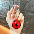 Soccer ball keychain in red and black pattern held by hand with silver metal ring - Single Pendant Style / Red