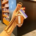 Détail du porte-clés ballon de rugby avec texture cuir, sangle tressée et crochet bronze - Ballon de rugby