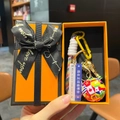 Close-up of World Cup trophy keychain in a premium gift box with soccer ball charm - Soccer Ball + Trophy + Sign + Red Braid + Orange Gift Box