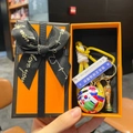 Close-up of golden trophy and colorful soccer ball keychain in an orange gift box - Soccer Ball + Trophy + Sign + Yellow Braid + Orange Gift Box