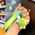 Cartoon tennis ball keychain featuring a green mascot holding a blue racket with a wristband - Tennis Style