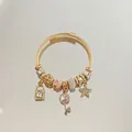 Macro view of gold woven steel bracelet featuring pink zircon stars and key charms - Gold Pink Star Key Rhinestone Bracelet