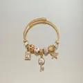Detailed macro view of gold-plated star and key charms on a spiral textured bracelet - Gold White Star Key Rhinestone Bracelet