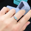 Nahaufnahme eines natürlichen Opalrings mit Diamanten auf Hand vor Geschenkbox - Verstellbar / Weißgold