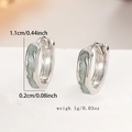 Macro shot of silver hoop earrings with green wavy enamel pattern and size measurements - 33