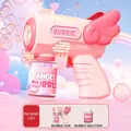 Pink angel wings bubble gun toy with refill bottle on a dreamy pastel sky background - Angel Pink Bubble Machine