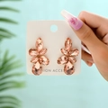 Close-up of champagne crystal leaf earrings with gold-tone claw setting on card - Pink