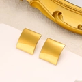 Macro detail of minimalist 18K gold plated square stud earrings on luxury white display - Polished Square Style