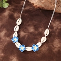 Bohemian surf necklace with white seashells and blue plumeria flowers on brown fabric - Qnn0018 - Blue Seashell Necklace