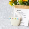 Detail of a beige straw woven mini bag for kids with colorful pom-pom decor and thin strap - Lace Color Balls - Cream