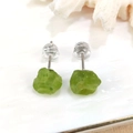 Vista macro di orecchini a perno in pietra grezza con chiusure in silicone su piatto bianco - Stile 3 Peridoto Verde Perno in Argento Sterling 925