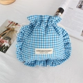 Detail of blue plaid drawstring bag with ruffle edges on a white textured background - Lake Blue Plaid