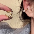 Minimalist gold-plated C-shaped ear cuff with white pearl detail shown worn on ear - Ear Cuffs / Gold