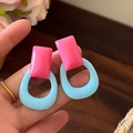 Primer plano de pendientes retro geométricos de resina rosa y azul en la mano - Geométrico Cuadrado Redondo / Rosa & Azul