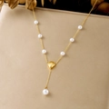 Gros plan d'un collier en Y en acier inoxydable doré avec perles et pendentif coquillage. - Collier Serpent en Y Perle Artificielle Saint-Jacques (N4196)