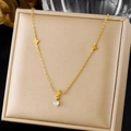 Gros plan du collier en acier doré avec breloques étoiles et pendentif en cristal. - Collier Zirconia Rond Étoile à Quatre Pointes en Acier Inoxydable (N4192)