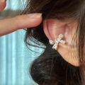 Gros plan d'un ear cuff nœud en zircons brillants porté sur le cartilage de l'oreille - Oreille droite / Argent