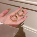 Primo piano di eleganti orecchini a cerchio dorati a forma di C tenuti in mano - Perno in Argento (12#)