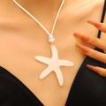 Detail view of a large white starfish pendant on a woven cord necklace for holiday style - White (8383)
