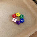 Detail of colorful beaded flower ring with vibrant petals on a kraft paper background. - Ring / Multicolor Flower
