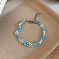 Detail view of a handmade blue and white beaded flower bracelet with green translucent beads - Bracelet / White-Blue