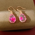 Detailed macro view of gold teardrop resin earrings with embedded pink dried flowers - Gold-Rose Red