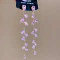 Nahaufnahme eleganter langer rosa Zirkon-Ohrringe mit funkelnden Akzenten aus Kristall - Rosa