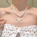 Close-up of a white resin starfish pendant necklace with a delicate organza cord. - White