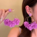 Detailed close-up shot of oversized purple fabric floral hoop earrings worn by a model. - Purple