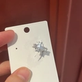 Detailed macro shot of a sparkling silver zircon cross ear cuff on a white display card - Cross Ear Cuff / Silver