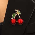Elegant red cherry brooch with green leaves pinned on a stylish black blazer jacket - Double Cherry (6348) / Gold